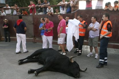 Varias personas contemplan el toro muerto tras chocar con otro en el segundo encierro de las fiestas patronales de Leganés.