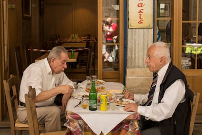 Dos hombres comen en una taberna.