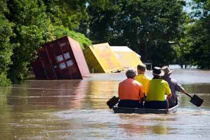 Un grupo de trabajadores se desplaza en una barca para comprobar una casa inundada in Beenleigh (Australia).
