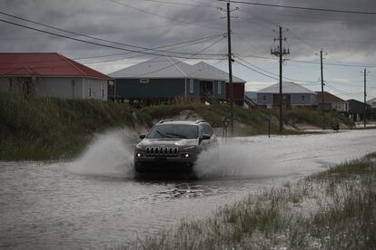 Un vehículo recorre una calle inundada en la isla de Dauphin, Alabama.