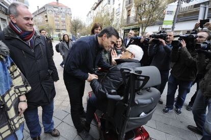Pedro Sánchez, candidato del PSOE a presidente del Gobierno,saluda en Vitoria a una persona en silla de ruedas.