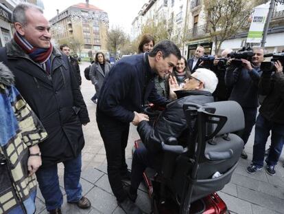Pedro S&aacute;nchez, candidato del PSOE a presidente del Gobierno,saluda en Vitoria a una persona en silla de ruedas.