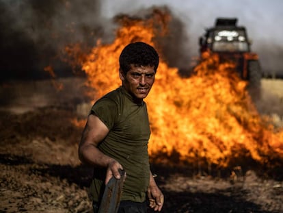 Un grupo de personas combate un incendio en un campo agrícola en la villa de al-Qahtaniyah, cerca de la frontera entre Siria y Turquía.