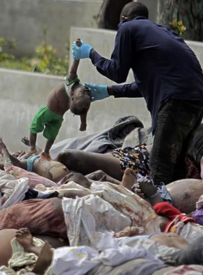 Un hombre coge el cadáver de un niño de entre los cuerpos depositados junto a un hospital de la capital.
