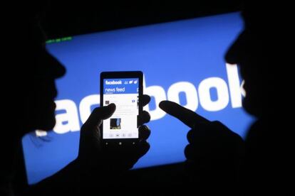 Dos usuarios consultan Facebook desde el móvil.