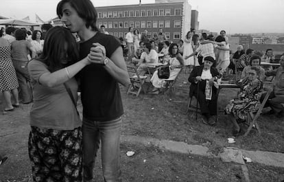 Una pareja joven baila en la verbena popular ante la atenta mirada de unos mayores.