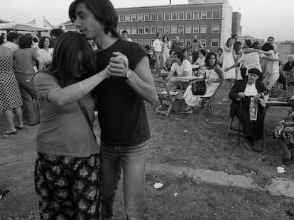 Una pareja joven baila en la verbena popular ante la atenta mirada de unos mayores.