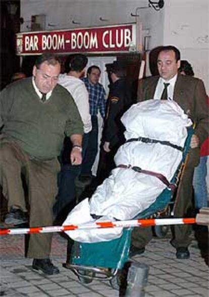 Miembros del servicio funerario trasladan el cadáver de la fallecida.