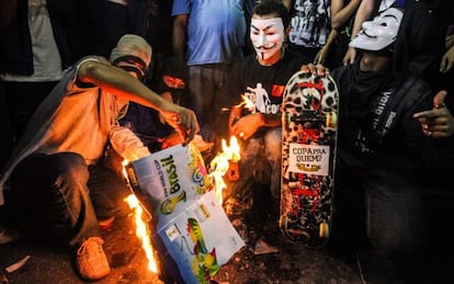 Grupo de manifestantes queima um &aacute;lbum da Copa no Rio.