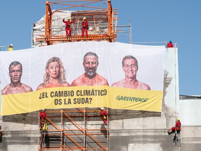 Varios activistas de Greenpeace cuelgan una lona en la Puerta de Alcalá, en Madrid, este martes.