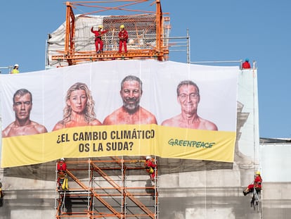 Varios activistas de Greenpeace cuelgan una lona en la Puerta de Alcalá, en Madrid, este martes.