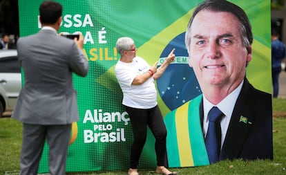 Apoiadora posa em frente a banner que promove o Aliança pelo Brasil.