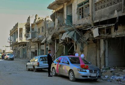 Un joven iraquí al lado de un automóvil, decorado para la primera boda en la antigua ciudad de Mosul, un año después de que el gobierno iraquí recuperase el control de la ciudad.