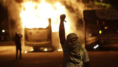 Manifestante gesticula próximo a ônibus incendiado no Rio. Polícia dispersou manifestantes com bombas de gás.