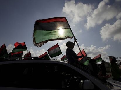 Un joven, sentado sobre el parabrisas de un coche, hace ondear la bandera libia durante una manifestación en Bengasi, el 31 de marzo de 2011.