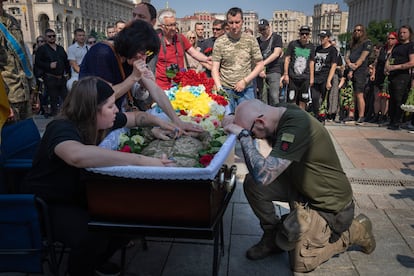 A serviceman pays his last respects at the coffin of a volunteer soldier killed in a battle with the Russian troops near Bakhmut, during a farewell ceremony in Independence Square in Kyiv, on June 20, 2023.