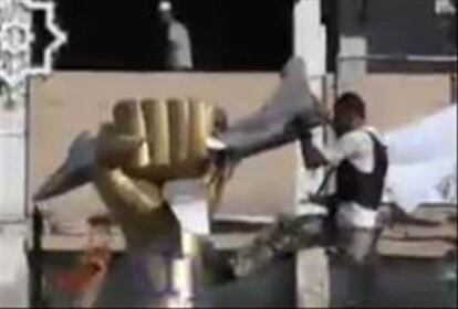 Imágen cedida por el canal de televisión emiratí Al Arabiya que muestra a un opositor que intenta derribar una estatua simbólica del palacio cuartel de Bab El Aziziya en Trípoli, en Libia