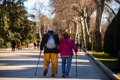 Dos personas mayores paseando con bastón por El Retiro, en Madrid.