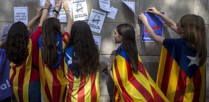 Varias estudiantes enganchan carteles en la pared de la Universidad de Barcelona durante el inicio de la "Maratón por la democracia".