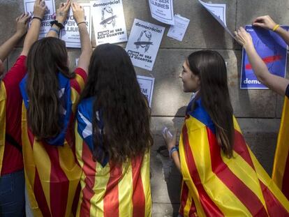 Varias estudiantes enganchan carteles en la pared de la Universidad de Barcelona durante el inicio de la "Maratón por la democracia".