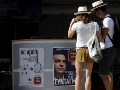 Touristas frente a un puesto electoral de Syriza, hoy en Atenas