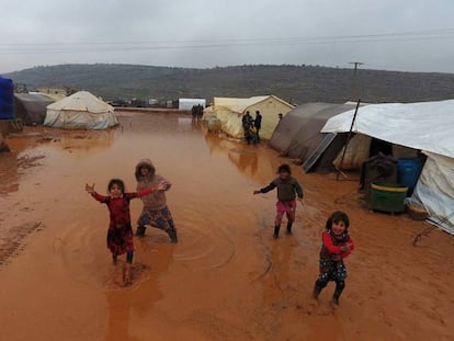 Niños sirios junto a las tiendas de un campamento de refugiados inundado, el domingo en Idlib.