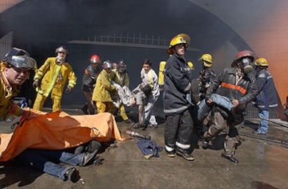 Varios bomberos rescatan y cubren los cadáveres de algunas de las víctimas en el incendio de un centro comercial de Asunción.