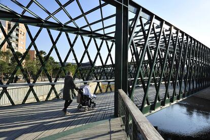 Paseantes en el puente Verde en Y, pasarela que tiene dos brazos en el margen izquierdo del Manzanares y uno en el derecho.