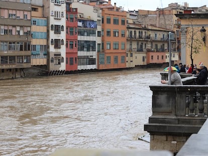 Vecinos de Girona observan una crecida del río Onyar a su paso por la ciudad.