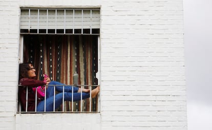 Una joven toca una guitarra pequeña sentada en la ventana de su vivienda en Córdoba, hoy lunes, inicio de una nueva semana de confinamiento por la crisis de la covid-19.