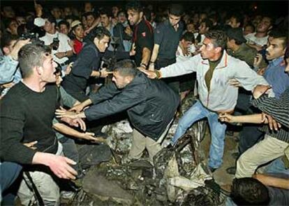 Grupos de palestinos, anoche, junto a los restos del coche atacado por helicópteros israelíes.