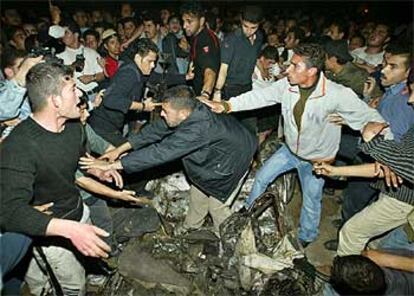 Grupos de palestinos, anoche, junto a los restos del coche atacado por helicpteros israeles.