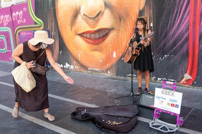 Una viandante da una moneda a Greta Borszewski, "Grex", el martes por la tarde en la Gran Vía de Madrid mientras interpreta "Sitting on the Dock of the Bay"