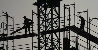 Un par de trabajadores trabajan en andamios en un edificio residencial.