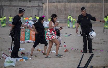 Unos agentes invitan a dos chicas a abandonar la playa de Nova Icària.