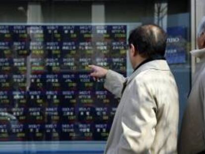 Dos viandantes observan varios valores bursátiles mostrados en una pantalla en el centro de Tokio. EFE/Archivo