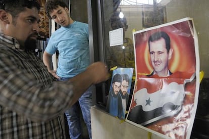 Un hombre coloca fotografías del líder de Hezbolá, y del presidente sirio Bachar el Assad en un establecimiento en Beirut.