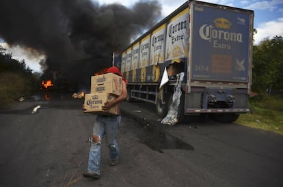 Un saqueador del cartel 'Caballeros Templarios' se lleva cajas de cerveza de un camión en llamas en Tierra Caliente (México), 10 de enero 2014.