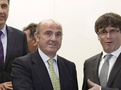 El presidente de la Generalitat, Carles Puigdemont saluda al ministro de Economía, Industria y Competitividad del Gobierno, Luis de Guindos, en presencia del presidente del PPC, Xavier Garcia Albiol.