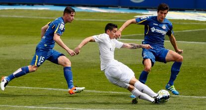 El centrocampista colombiano del Real Madrid James Rodríguez (c), entre los defensas del Getafe, Santiago Vergini (d) y Carlos Vigaray (i).