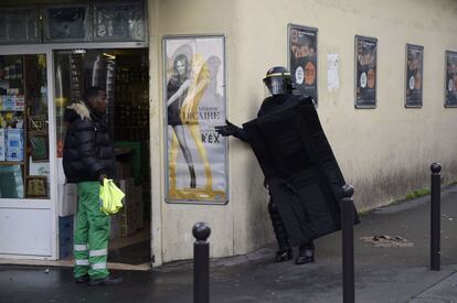 Un agent de la Policia francesa parla amb un veí a prop de la comissaria atacada a París.