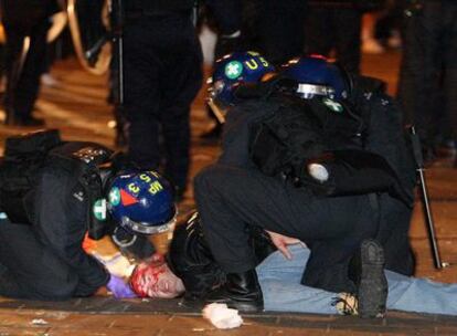 Dos agentes atienden a un hombre herido durante los disturbios.