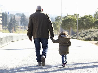 Un jubilado camina por un parque con una niña.