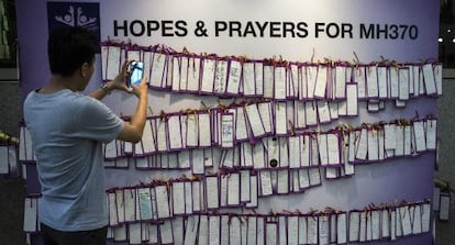 Un joven fotografía mensajes de apoyo a los pasajeros del vuelo MH370.