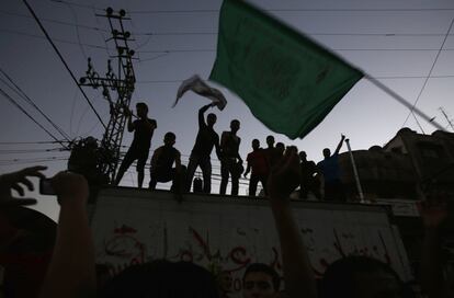 Un palestino muestra su bandera de Hamás mientras otros celebran el anuncio de paz que ha hecho Israel la tarde de este martes.