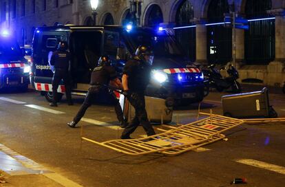 Un grupo de policías retira contenedores y vallas lanzadas por los manifestantes en los disturbios de anoche en Barcelona.