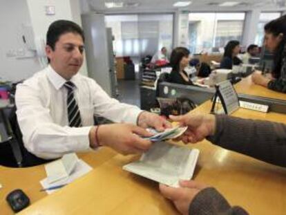 Un empleado de una sucursal del Banco Laiki entrega el dinero retirado por uno de sus clientes en Nicosia (Chipre).