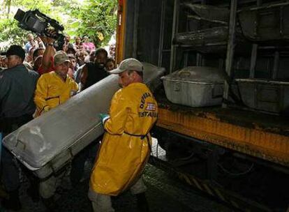Empleados municipales transportan los ataúdes de los tres cooperantes franceses asesinados el martes en Río.