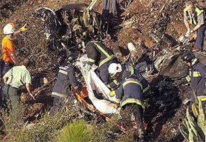 Bomberos, policías y guardias civiles rescatan el cadáver de uno de los fallecidos en el accidente del helicóptero.