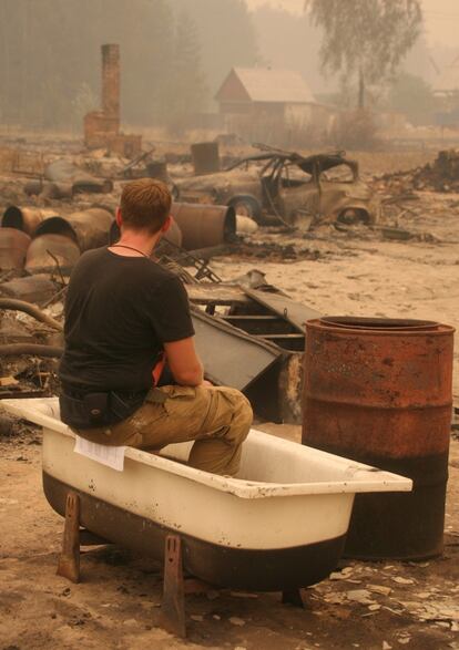 Un hombre observa sentado en una bañera lo que queda de sus pertenencias, después de que el fuego arrasara su casa en el pueblo de Kriusha, a unos 270 kilómetros al sureste de Moscú.